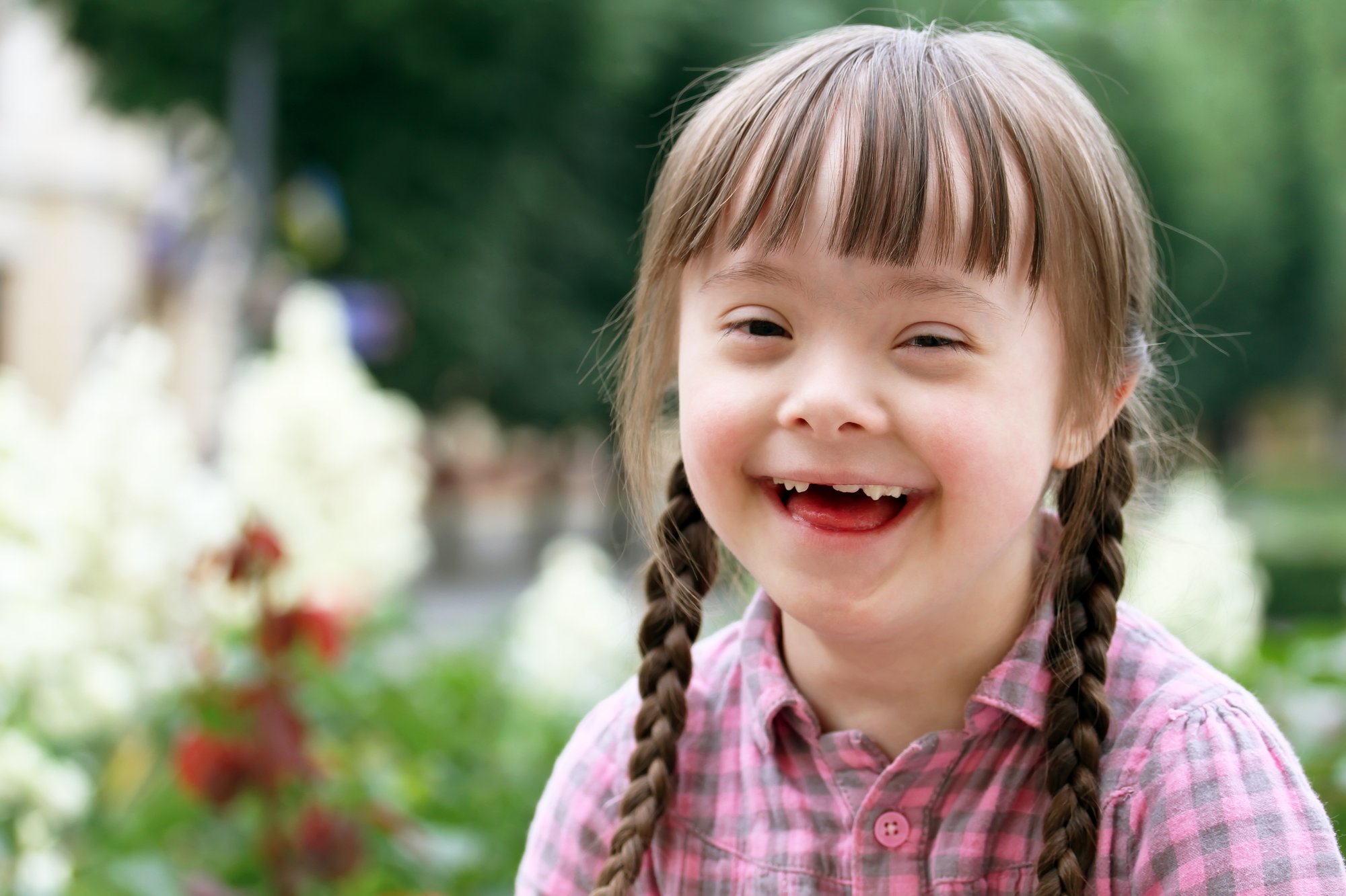 Pathlight Fund. A portrait of a young girl with Down Syndrome and a light skin tone smiles widely. 